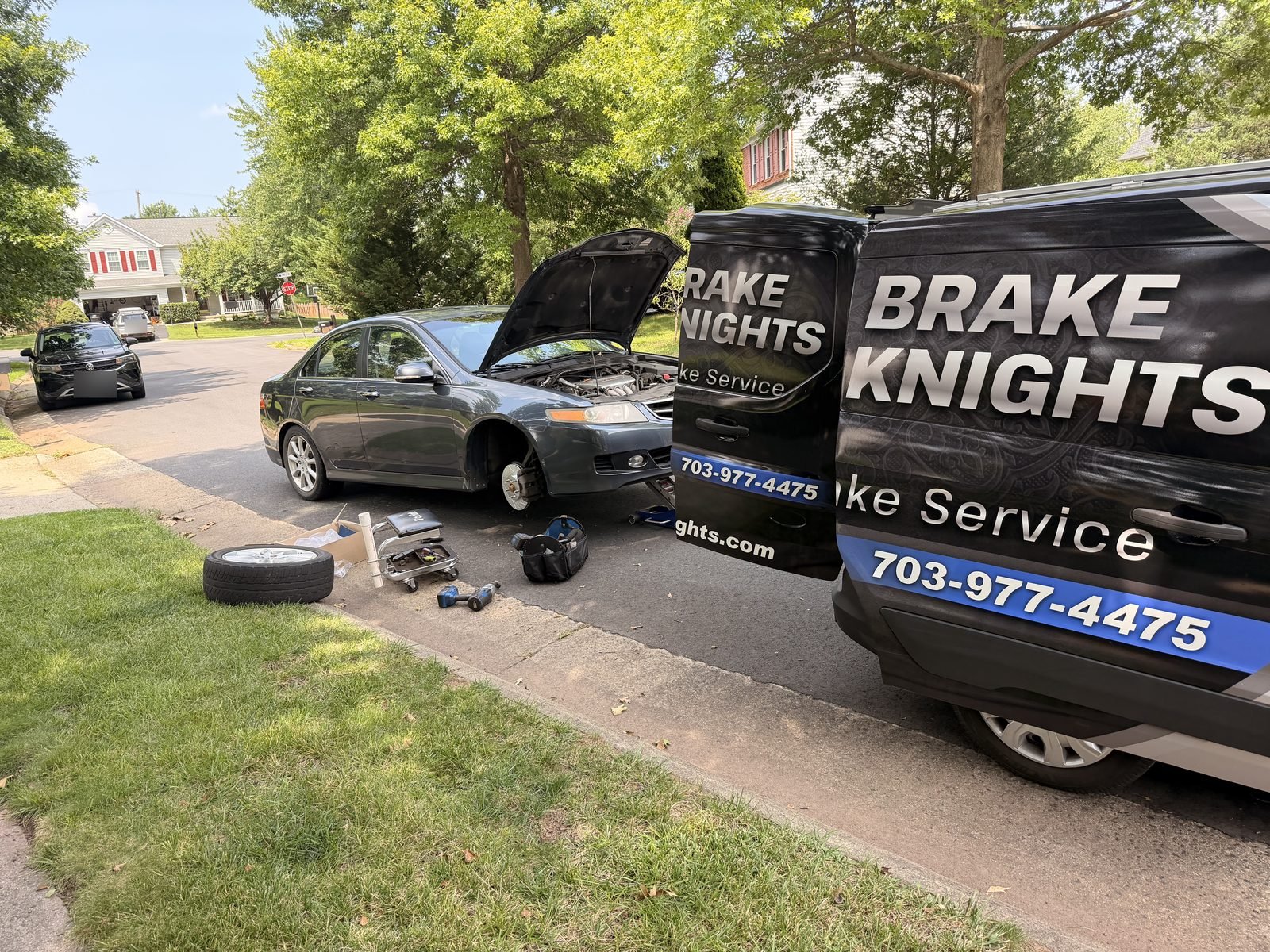 Brake Knights service van parked at an Ashburn home with a customer's sedan raised for front brake replacement